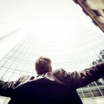 Employee - low-angle photography of man in the middle of buidligns