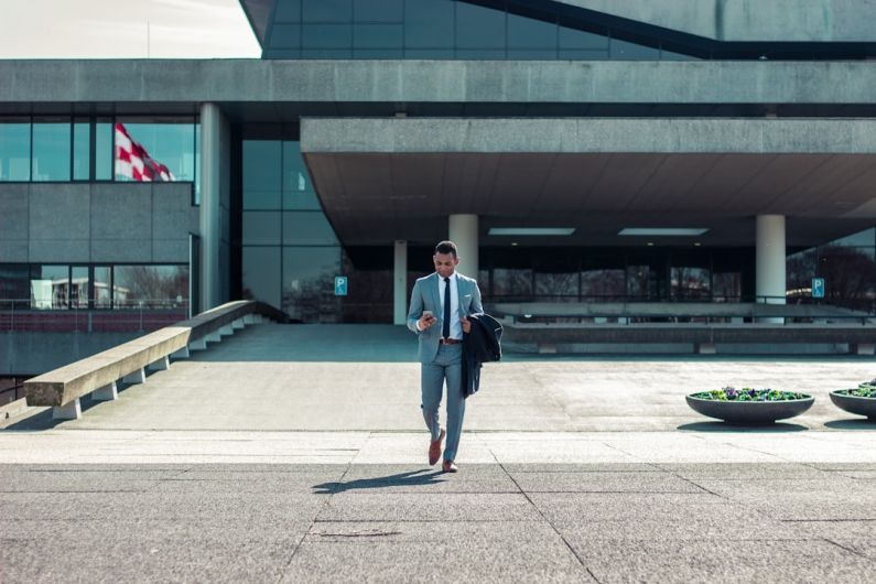 Leadership Business - man walking while holding black coat