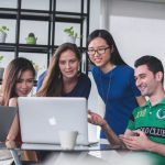 Leadership Business - four people watching on white MacBook on top of glass-top table
