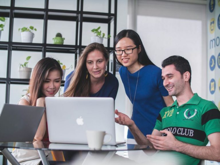 Leadership Business - four people watching on white MacBook on top of glass-top table