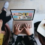 Marketing - person using microsoft surface laptop on lap with two other people