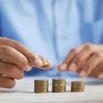 Investing - a person stacking coins on top of a table