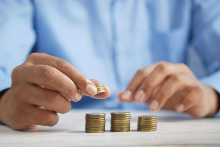 Investing - a person stacking coins on top of a table