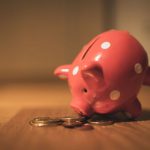 Invest - pink pig coin bank on brown wooden table