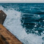 Dropshipping - Detail of shabby wooden boat sailing in blue sea and splashing water in summer