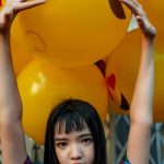 Model - Woman Wearing Blue Top Standing in Front of Yellow Balloons