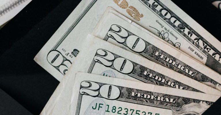 Tax Reductions - Stack of dollars and black envelope with banknotes inside