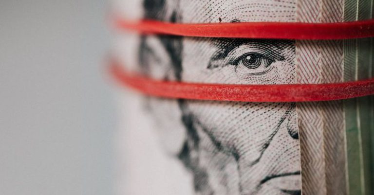 Trade Wars - Closeup of rolled United States five dollar bills tightened with red rubber band