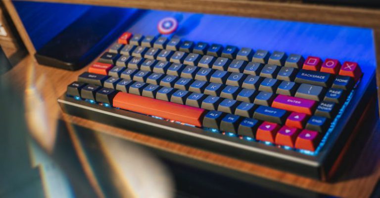 Ergonomic Workspaces - From above contemporary mechanical keyboard of black and red colors with lightning placed on wooden computer desk