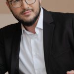 Negotiations - A Bearded Man in Black Suit Wearing Eyeglasses