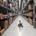 Inventory - Person Sitting on Ground Between Brown Cardboard Boxes